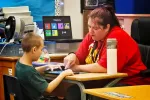 A picture of Melisa Smith working with a student in her classroom.