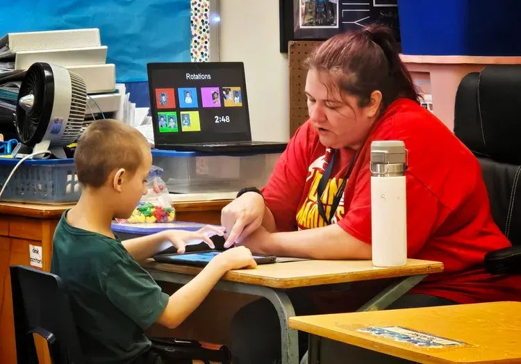 A picture of Melisa Smith working with a student in her classroom.