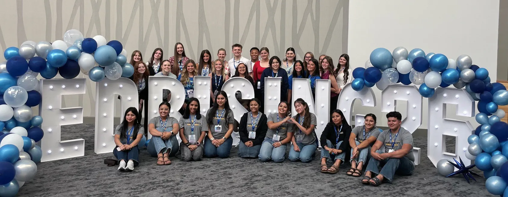 A group of Educators Rising Kansas students stand in front of a sign.