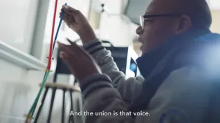 Black student with glasses sets up an experiment in a classroom with subtitle "And the union is that voice."