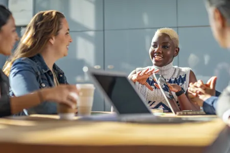 a diverse group of people sitting at a table conversing 