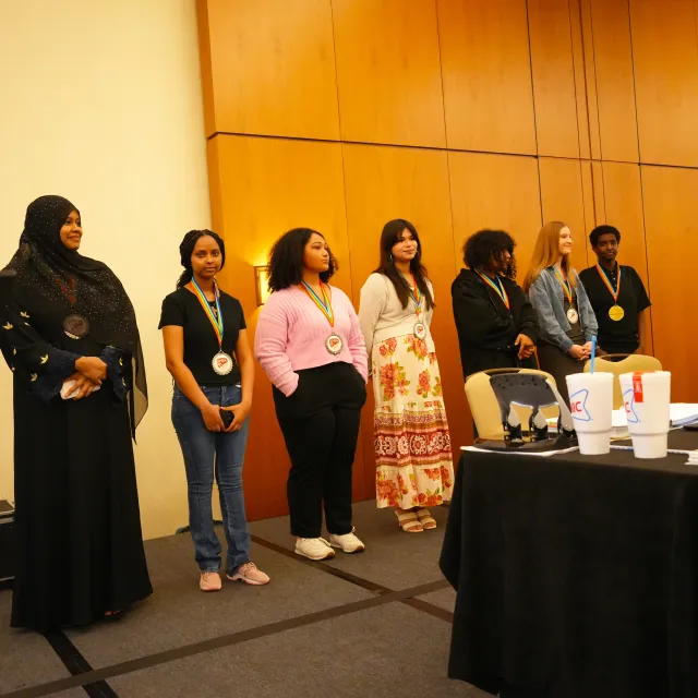 Winners from the 2026 Just Imagine Justice campaign standing in line on a stage